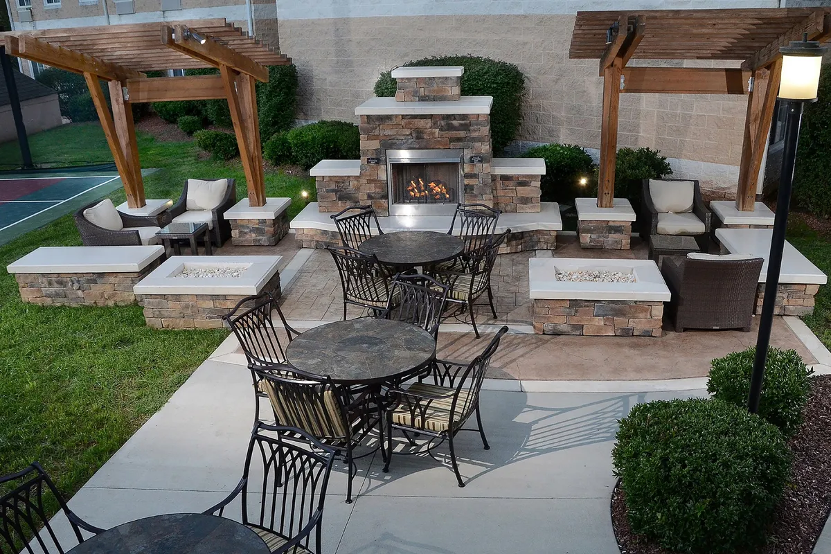 This exterior image captures an inviting outdoor seating area with a central fireplace, surrounded by comfortable chairs and tables. The space is designed for gathering with friends or family, offering a cozy atmosphere for evening relaxation after a busy day of exploring.