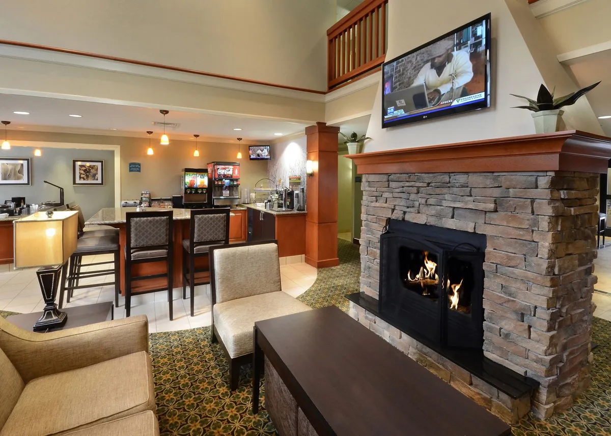 A warm, cozy interior featuring a fireplace, bar area, comfortable seating, and a television. The scene evokes a sense of communal gathering, relaxation, and casual socializing, with multiple zones for working, watching TV, or enjoying refreshments.