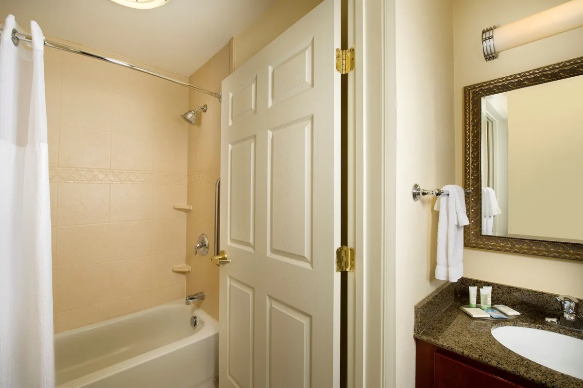 The photo features a bright, inviting bathroom with a large mirror, sink, and bathtub—evoking a sense of relaxation and rejuvenation. The clean, soothing setting hints at the comfort guests can experience after a day spent exploring Raleigh.